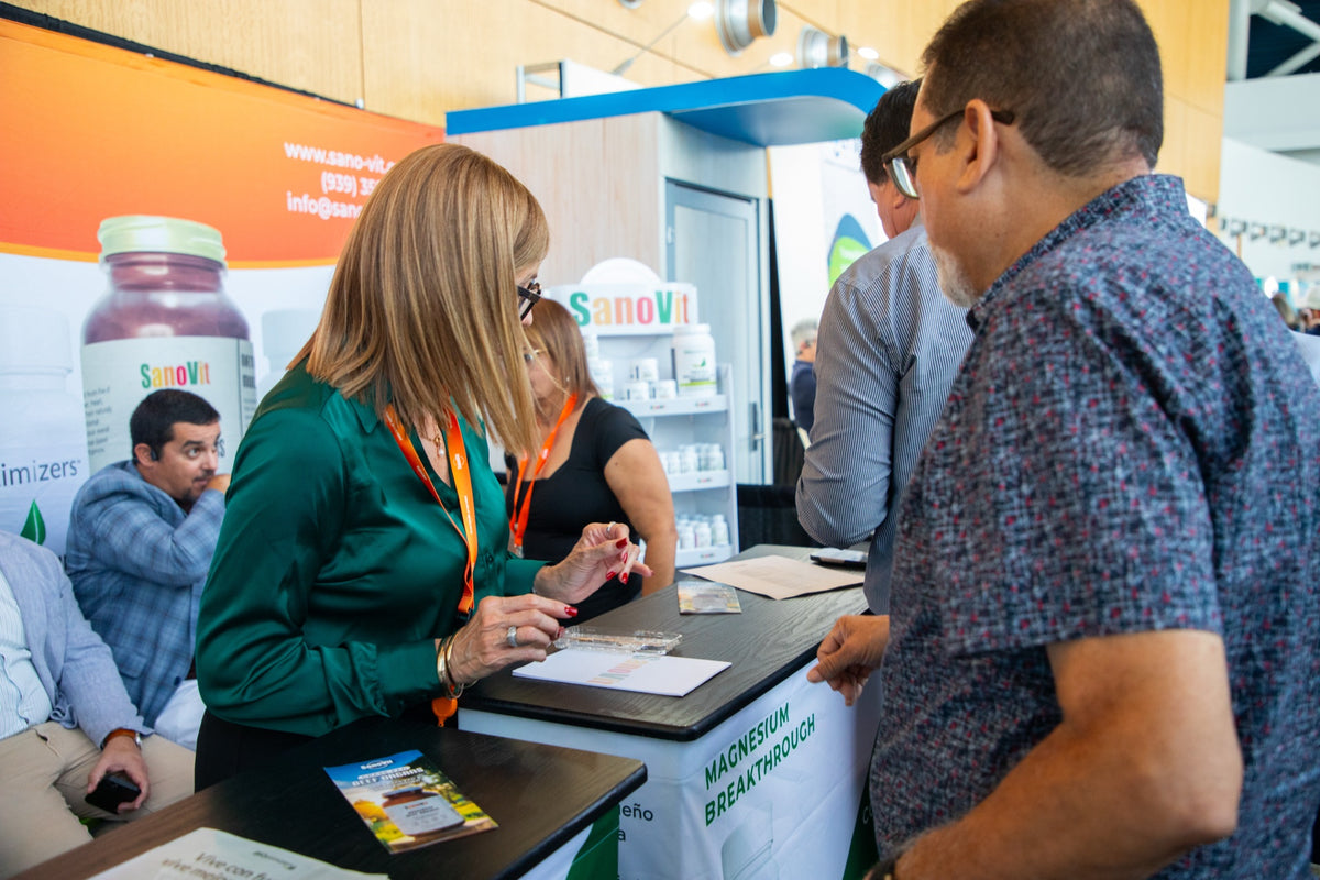 Representantes de SanoVit explican sus productos a un visitante.