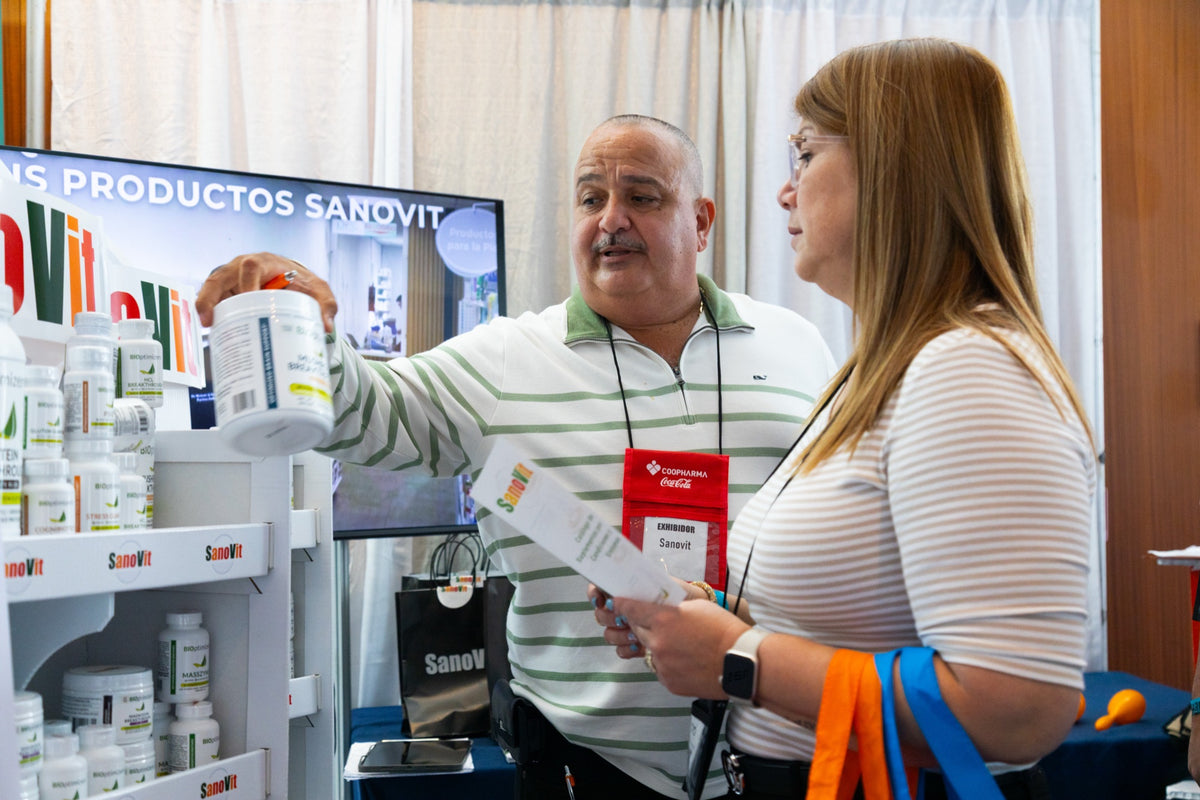 Representante de SanoVit muestra un producto a una visitante.